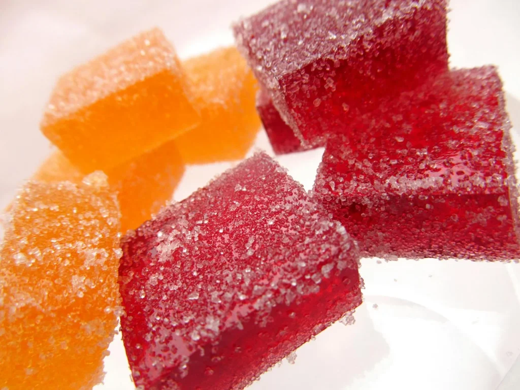 Slimmit酵素果凍為什麼選擇果凍劑型?3大優勢讓它成為主流 3 Bright and vibrant sugar-coated red and orange jelly candies in a close-up macro shot.