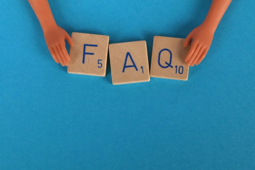 Slimmit酵素果凍常見問題FAQ 7 Flat lay of scrabble tiles spelling 'FAQ' with toy hands on a blue background, creating a conceptual